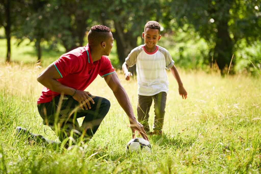 Sport Practice With Father Teaching Son How To Play Soccer