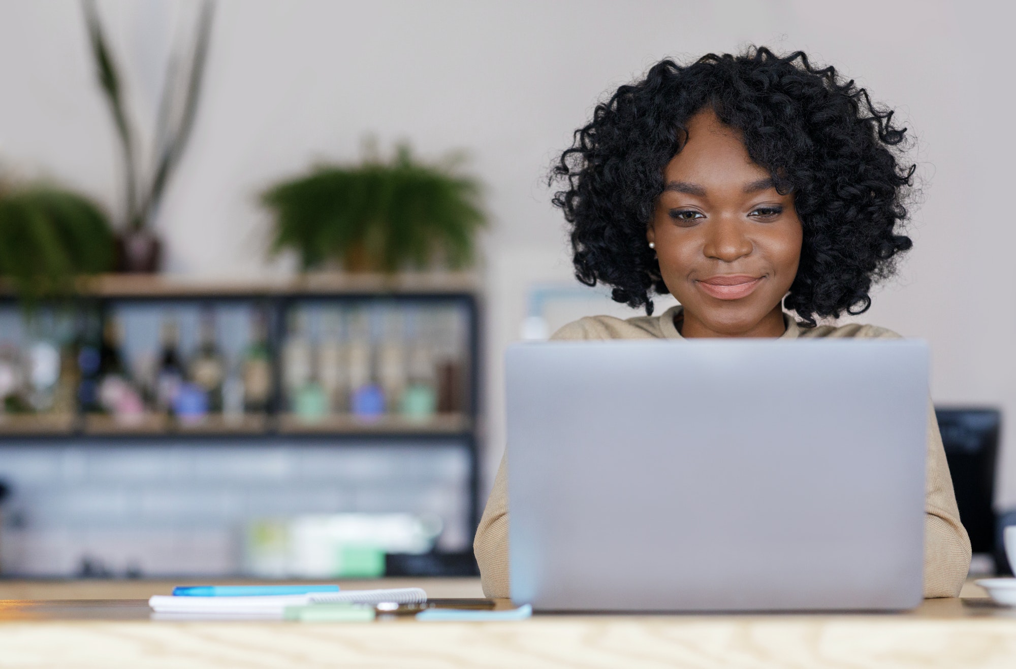 Black woman freelancer working with laptop at cafe