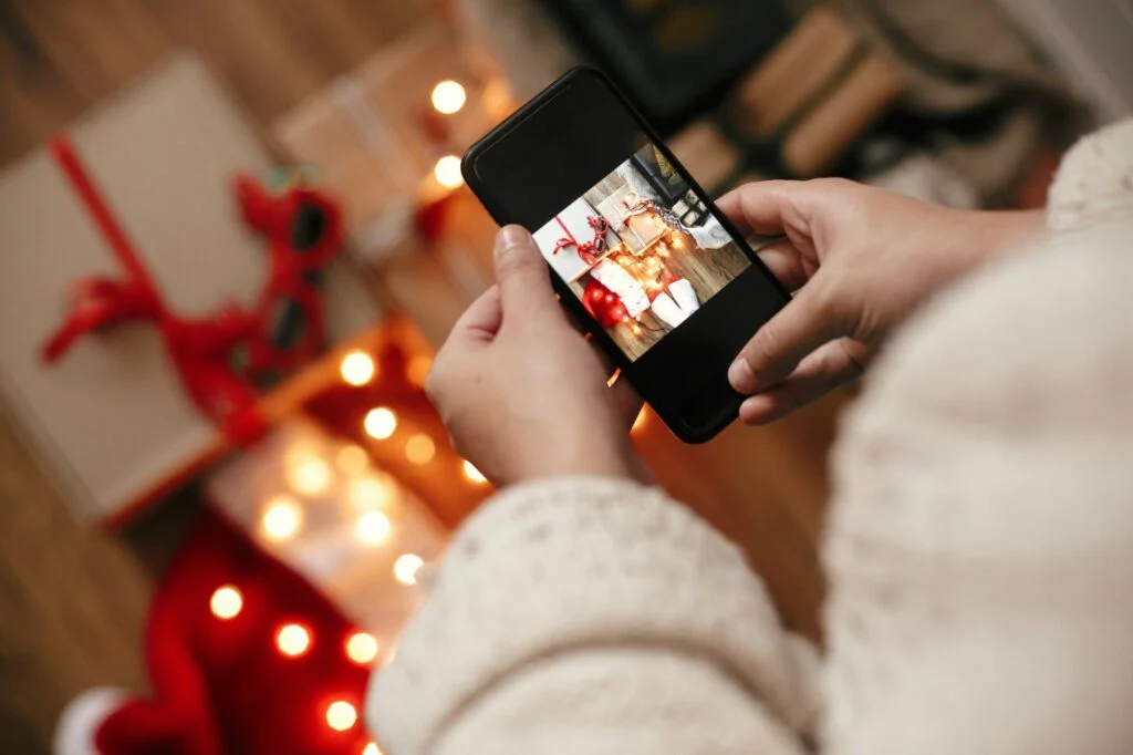 Hands holding phone and taking photo of christmas gift boxes